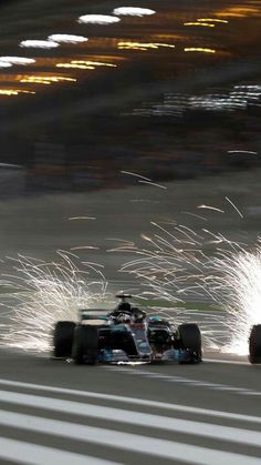 a car driving down a race track with fireworks in the air behind it and on top of its wheels