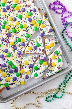 a pan filled with cake covered in white frosting and sprinkles next to beads