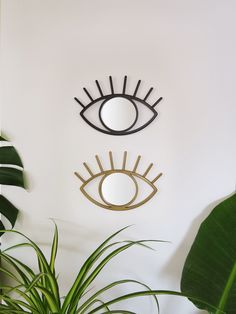 an eye shaped mirror hangs on the wall next to a potted plant