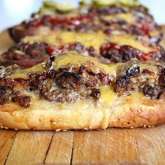 two pizzas with cheese and meat toppings sitting on a cutting board