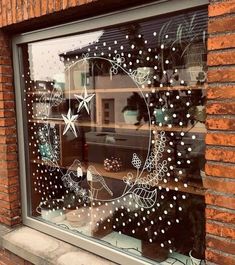 a window decorated with white stars and snowflakes, in front of a brick building