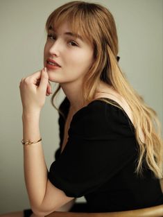 a woman sitting at a table with her hand on her chin and looking off to the side