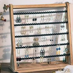 a wooden jewelry rack with earrings and bracelets hanging from it's sides on a table