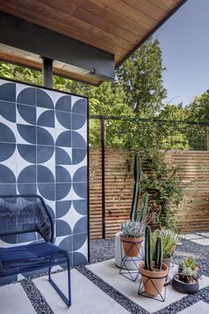 a blue chair sitting on top of a white rug next to a wooden fence and potted plants