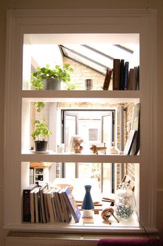 a bookshelf filled with lots of books next to a window