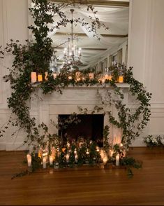 the fireplace is decorated with candles and greenery