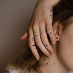 a woman with tattoos on her left hand and fingers behind her head is looking at the camera