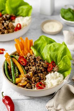 two bowls filled with meat and vegetables on top of a table