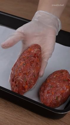 a person in white gloves is holding two sausages on a tray with plastic wrappers