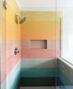 a bathroom with colorful tiles on the wall and shower head mounted to the side of the bathtub