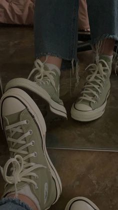 a person wearing green sneakers and ripped jeans