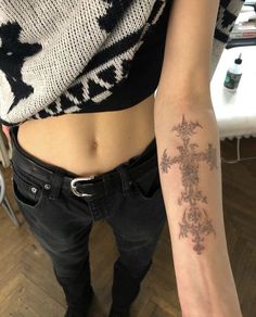 a woman with a cross tattoo on her left arm and the other arm behind her