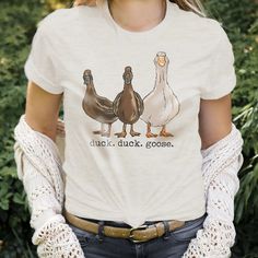 "\"duck.duck.goose\" Adult tee If you love feathered friends as much as your kiddoes, this tee is perfect! The entire family will love the realistic, fun artwork and adults will love the soft material and affordable price. Sizes available include: Men's Small, Men's Medium, Men's Large, Men's XL, Men's XXL **Clothing has been reviewed as true to size. FACTS YOUR CUSTOMERS WILL LOVE - We are a family company, woman and mom owned! - Our designs are all original artwork created from the inspiration we draw from our outdoor-loving kids!  - Our clothing is hand-printed in small batches in our shop right in Western North Carolina.  - Our clothing is made with a polyester/cotton blend that is SUPER SOFT and durable.  BFB Mission: We strive to make quality clothing your mini adventurers will love. Farm Fashion, Duck Duck Goose, Fun Artwork, Country Tees, Duck Duck, Western North Carolina, Cute Shirt Designs, Funny Shirt Sayings, Cute Comfy Outfits