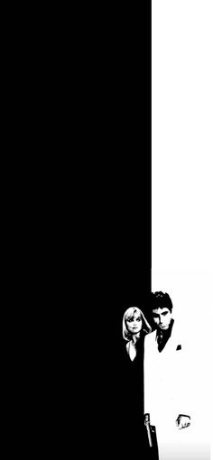 two people standing next to each other in front of a black and white wall with one person covering his face