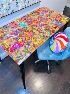 a colorful table and chair in a room with art on the wall behind it,