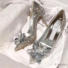 two pairs of silver high heel shoes with bows on the toes and heels are sitting on a white cloth