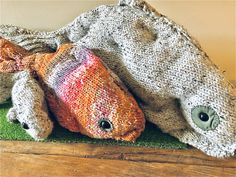 a knitted stuffed animal laying on top of a wooden floor next to a blanket