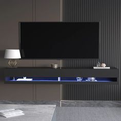 an entertainment center with a large television mounted on the wall and blue lighting underneath it