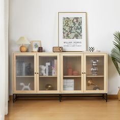 a wooden cabinet with glass doors on the top and bottom, next to a potted plant