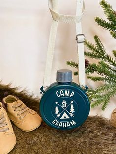 a camping flask hanging from the side of a tree with shoes next to it