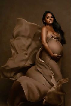 a pregnant woman laying on top of a bed under a blanket with a dog underneath her