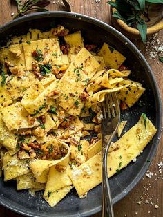 a skillet filled with pasta and sauce on top of a wooden table