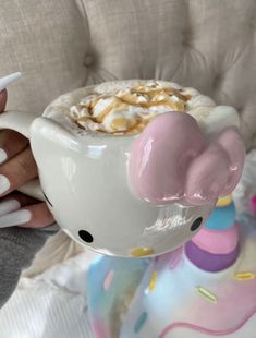 a person holding a cup of hot chocolate with marshmallows on top and an elephant decoration