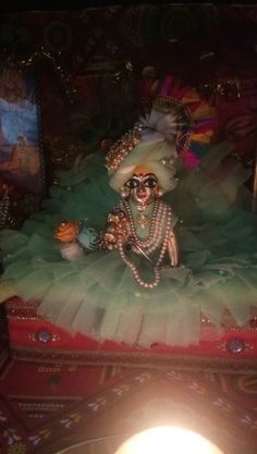 a statue in the shape of a woman wearing a green dress with pearls on her head