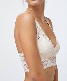 a woman wearing a white bra with lacy lace on the top and bottom, standing in front of a white background