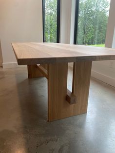 a large wooden table sitting inside of a living room next to a tall glass window