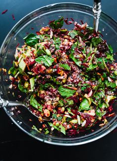 a glass bowl filled with spinach and cranberry salad on top of a table