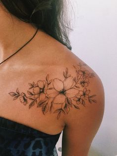 a woman's shoulder tattoo with flowers on her left arm and the upper half of her body