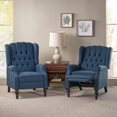 a living room with two blue chairs and a lamp on the side table in front of a window