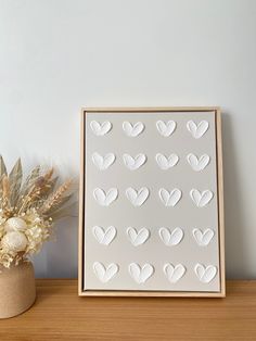 a white paper heart cut out on a wooden frame next to a vase with dried flowers