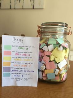 a jar filled with lots of colorful sticky notes next to a sign that says hey