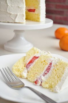 a piece of cake on a plate with a fork and oranges in the background