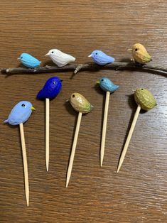 six small birds sitting on top of toothpicks in the shape of twigs