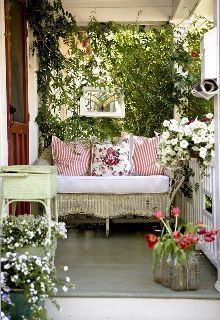 the porch is decorated with flowers and greenery