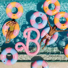 two people floating on inflatable rafts next to a swimming pool