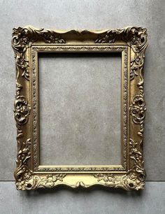 an ornate gold frame on the wall with a gray floor in front of it and grey walls behind it