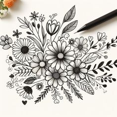 a drawing of flowers and leaves on a sheet of paper with a pen next to it