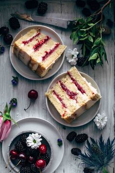 two slices of cake on plates with berries and flowers next to each other in the background