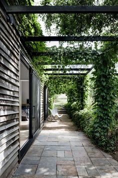 an outdoor covered walkway with brick pavers and green ivy growing on the side of it