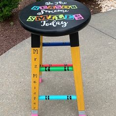 a black and yellow wooden stool with writing on the seat that says, summer today