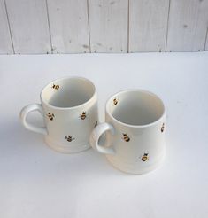 two white coffee mugs with bees on them