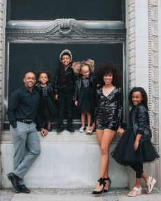 a group of people standing next to each other in front of a building with black clothing