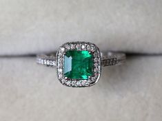 an emerald and diamond ring on display