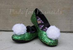 pair of green glitter shoes with white pom - poms