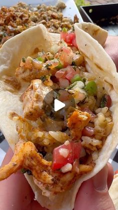 a person holding up a taco filled with meat, vegetables and other toppings