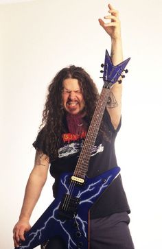 a man with long hair is holding his guitar up in the air and smiling at the camera